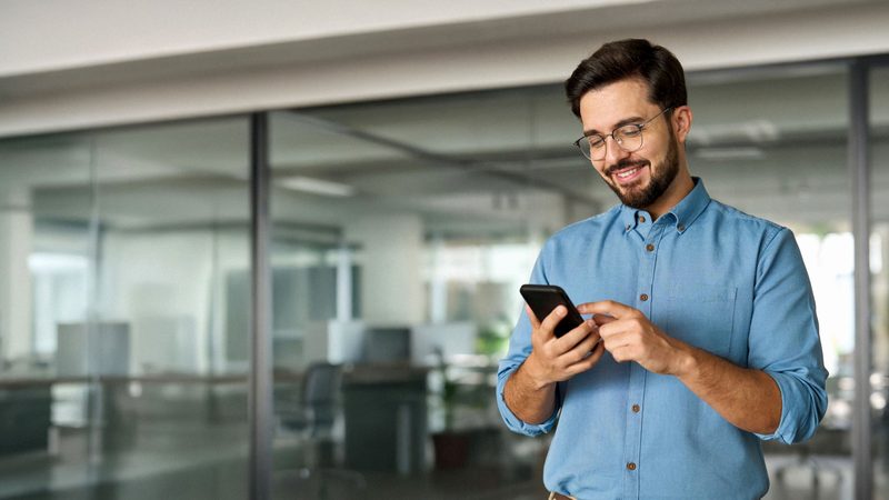 Hombre de negocios sonriendo mientras revisa su celular
